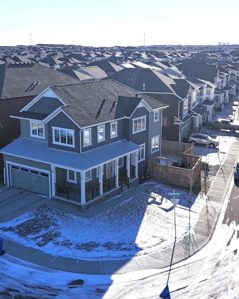 Aerial shot of two-story home in Calgary with snow-covered yard and new roofing.