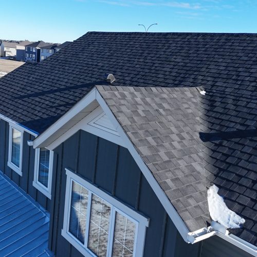 Gray siding home with fresh roofing and dormer windows.