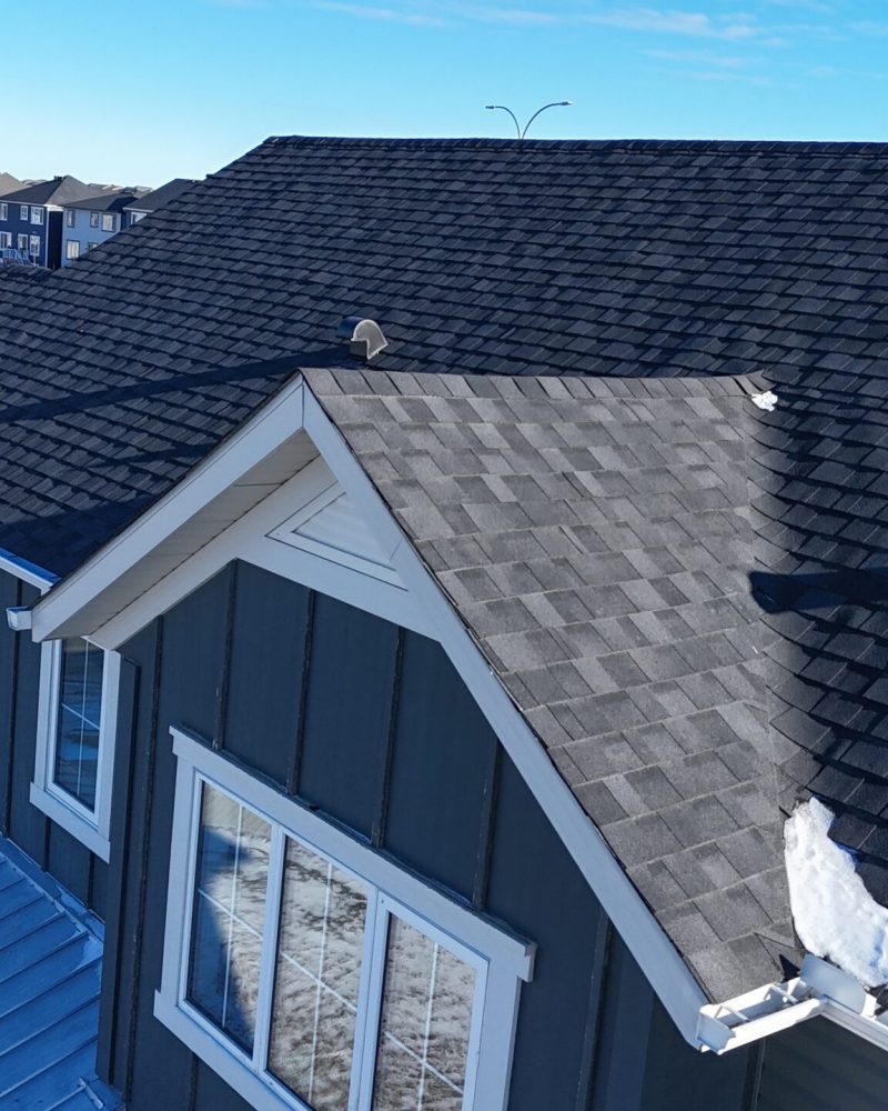 Dark asphalt roofing on Calgary home with white trim and dormer windows.